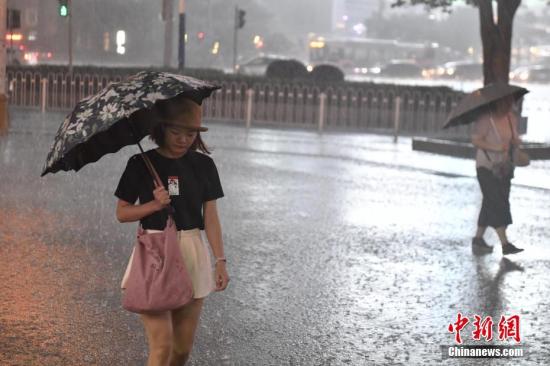 5月8日，广州城区受强雷雨云团影响，在下班高峰期下起暴雨，路人撑伞行走在雨中。中新社记者 陈骥旻 摄